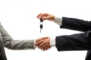 Car dealer giving keys of a new car to female buyer.